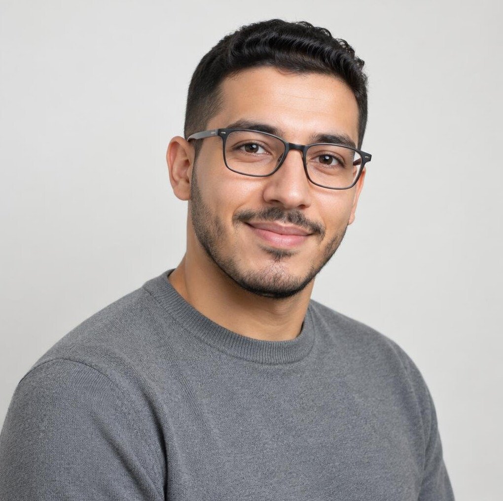 Portrait of a young man with glasses and dark hair wearing a gray sweater