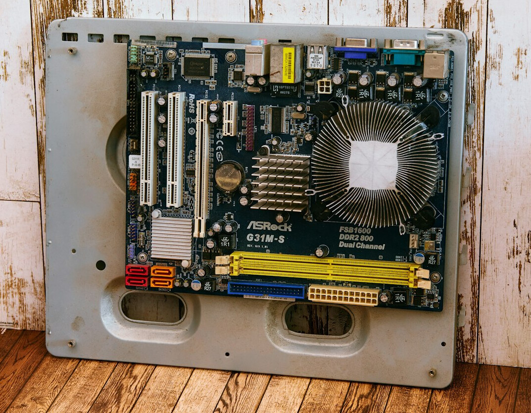 Open desktop computer with visible motherboard and fans being cleaned